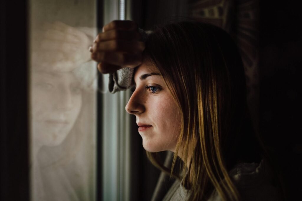 Woman looking contemplative by a window - mental health awareness