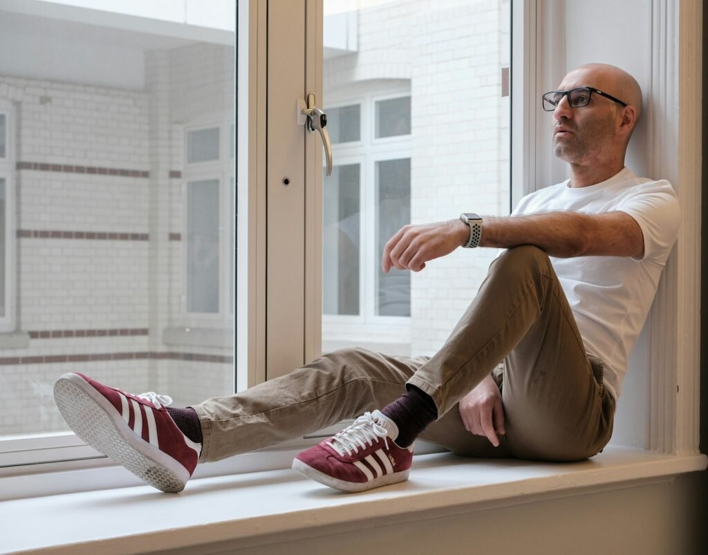 A man sitting quietly by a window, looking out in a moment of reflection