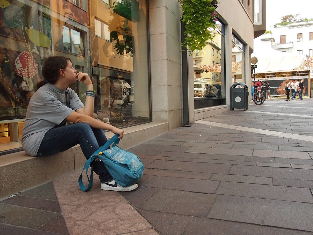 A teenager sitting alone outdoors, looking down in thought, illustrating the isolation that can come with relying on an AI companion app instead of real relationships.