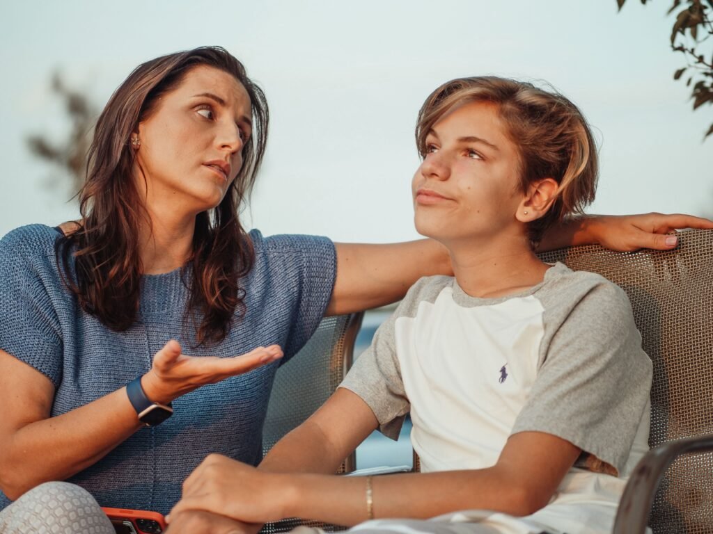 A mother and her teenage son sitting outside, deep in a calm, honest conversation.
